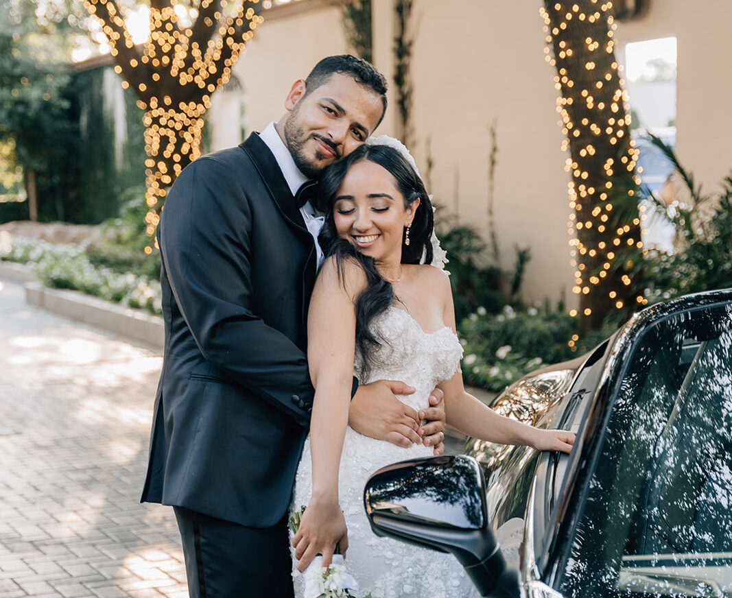 bride and groom pose by car on Houston Wedding day