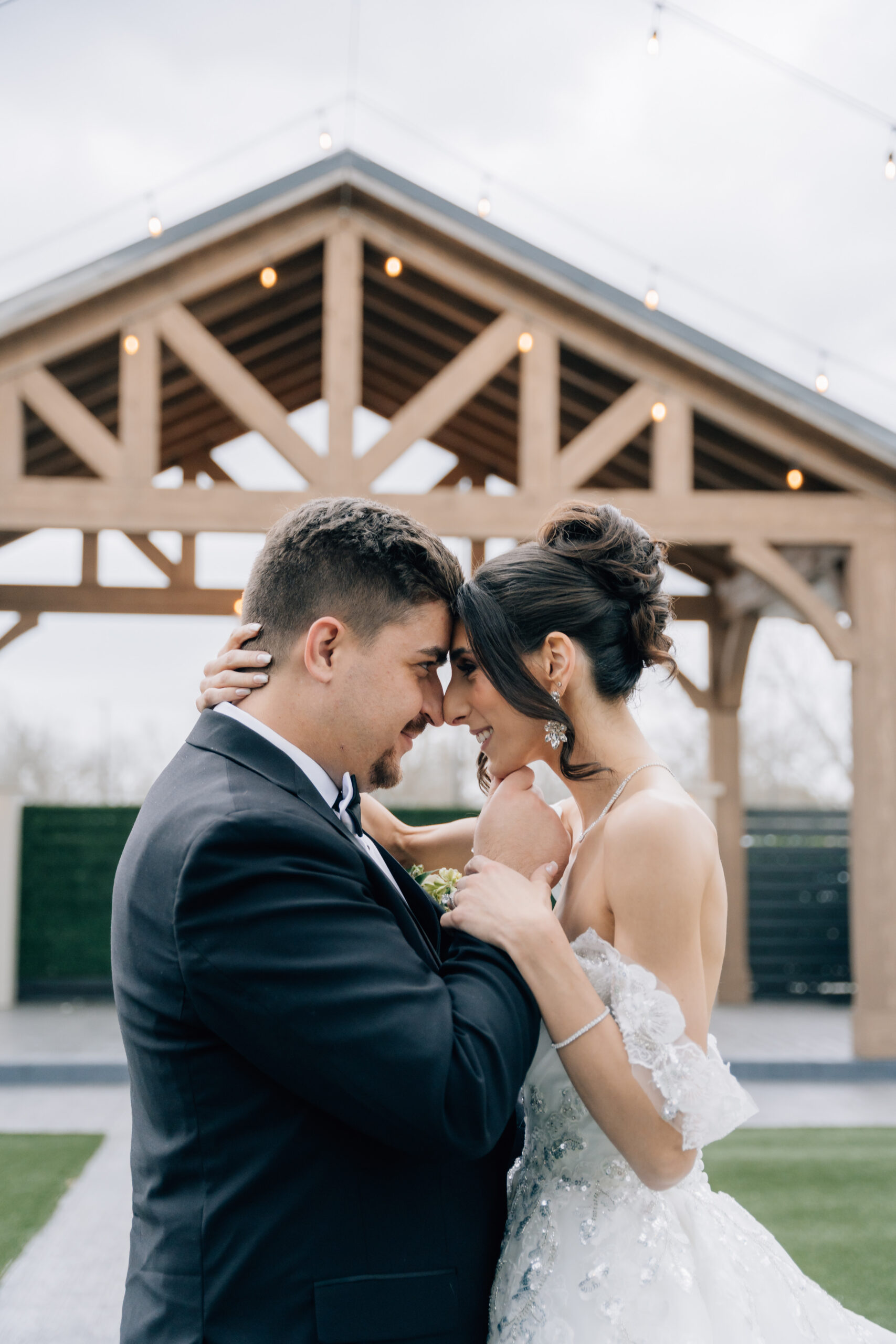 Editorial close-up portrait of a bride and groom touching foreheads under the pavilion at Stables on the Brazos.